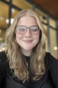 A woman wearing glasses and smiling. 